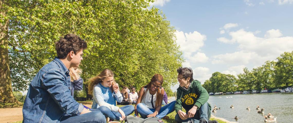 Junge Erwachsene sitzen auf einer Wiese in Oxford