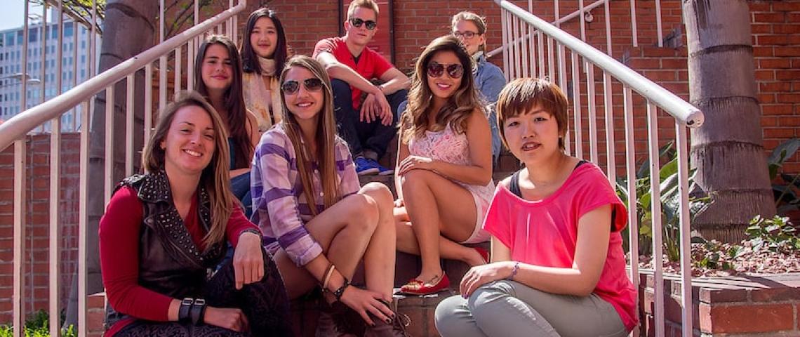 Sprachschüler sitzen vor Sprachschule auf Treppe